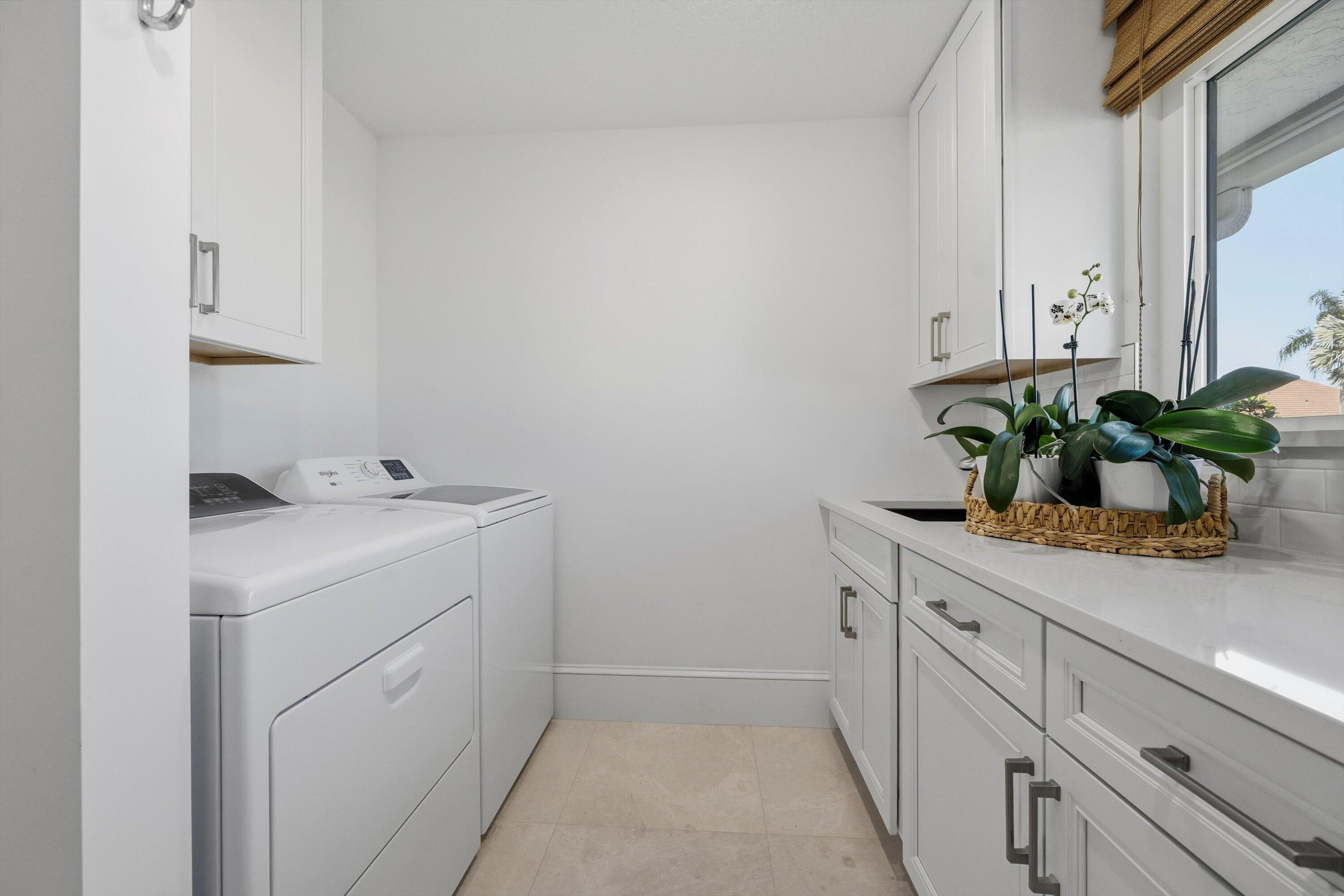 9039 Southeast Hawksbill Way Hobe Sound, FL 33455 - Photo 31 of 45 a utility room with cabinets washer and dryer