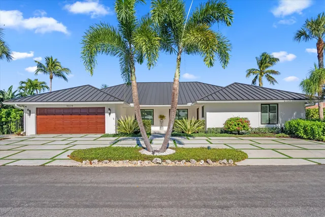 a front view of a house with a yard and potted plants