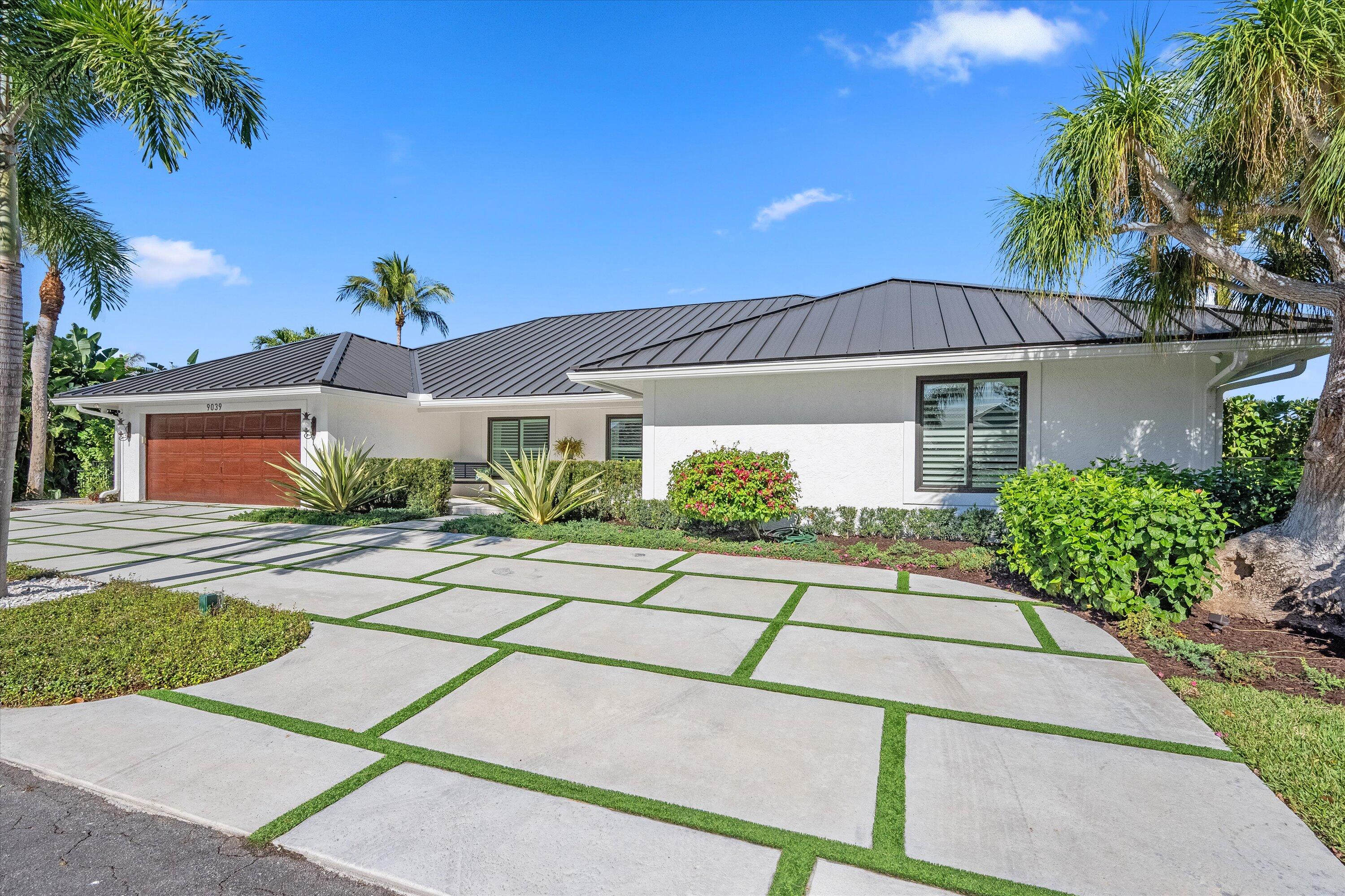 9039 Southeast Hawksbill Way Hobe Sound, FL 33455 - Photo 8 of 45 a front view of a house with a yard and potted plants