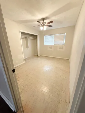 an empty room with a ceiling fan and a rug