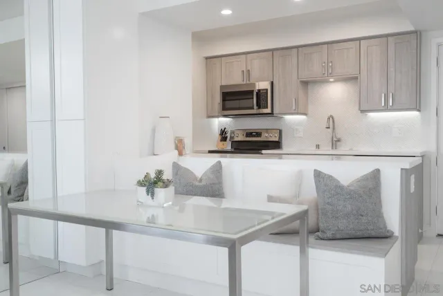 a kitchen with stainless steel appliances granite countertop a sink a microwave a refrigerator and white cabinets