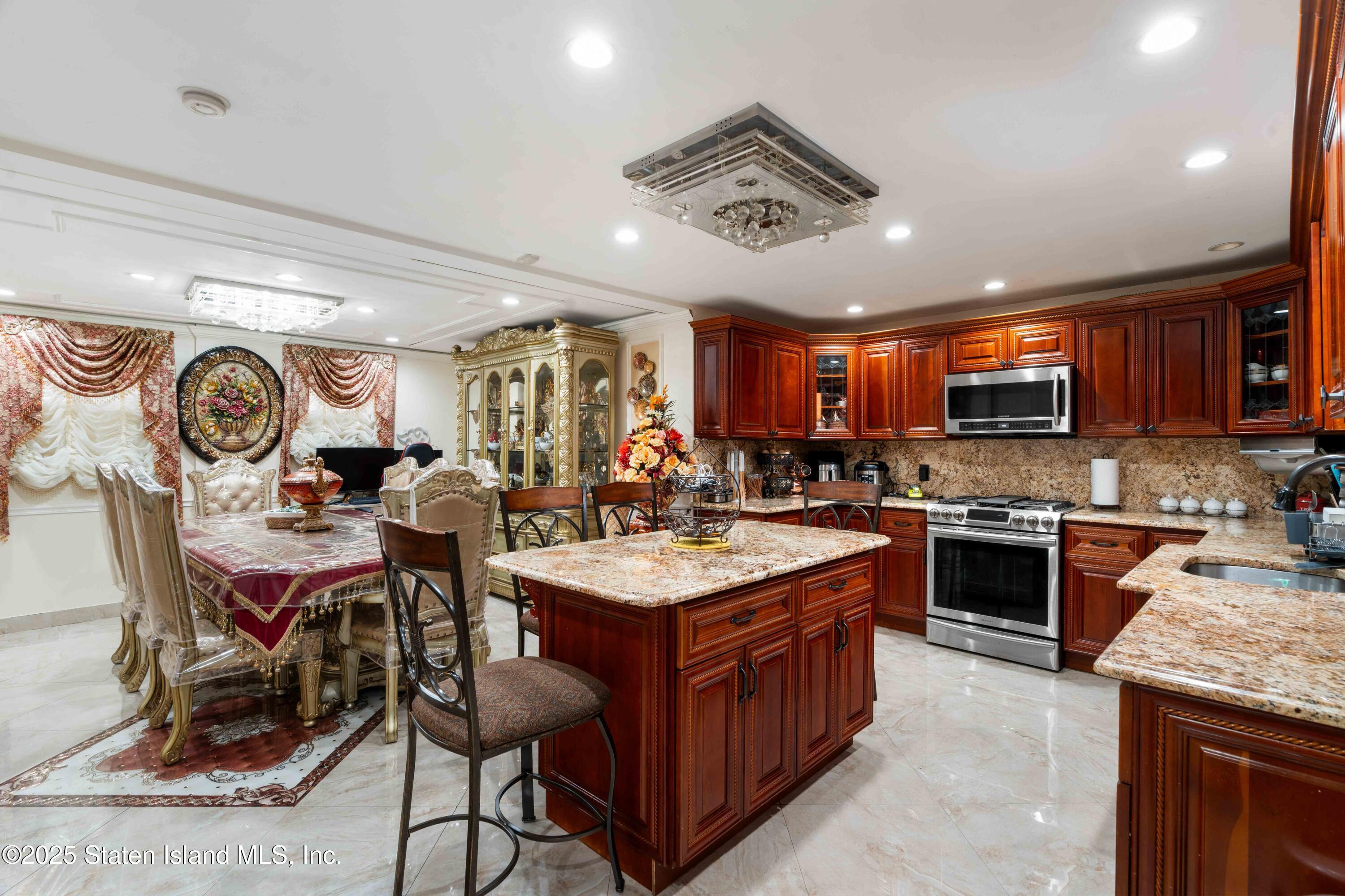 287 Rensselaer Avenue Staten Island, NY 10312 - Photo 32 of 35 a large kitchen with stainless steel appliances granite countertop a stove oven a sink dishwasher and a dining table with garden view