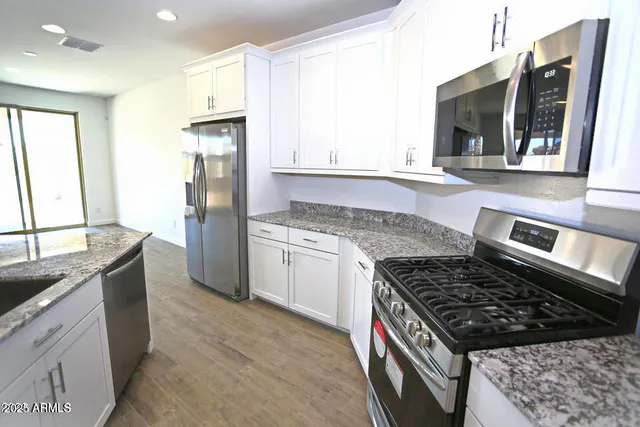 a kitchen with kitchen island granite countertop wooden cabinets and refrigerator