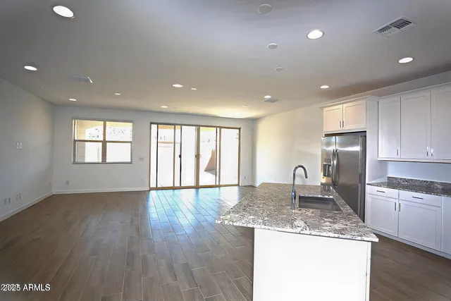 a kitchen with stainless steel appliances kitchen island granite countertop a refrigerator a sink and a stove