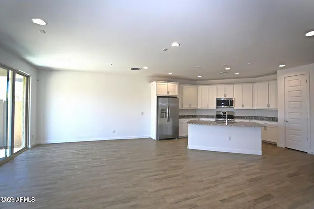 a kitchen with stainless steel appliances kitchen island granite countertop a refrigerator and a stove top oven