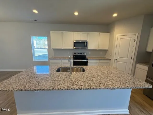 a kitchen with granite countertop kitchen island a sink appliances and cabinets