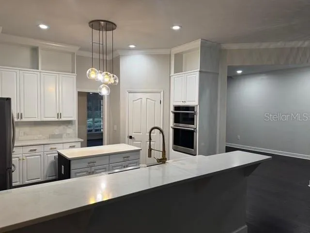 a kitchen with stainless steel appliances a sink cabinets and wooden floor