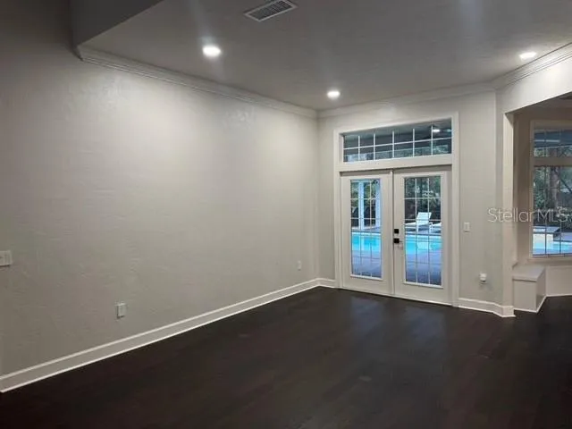 an empty room with wooden floor and windows