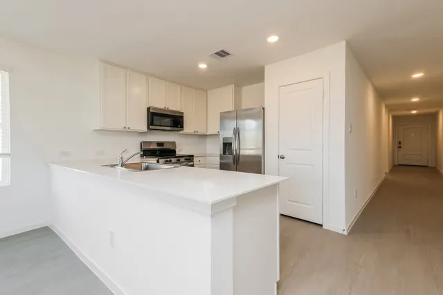 a kitchen with stainless steel appliances a refrigerator sink and white cabinets