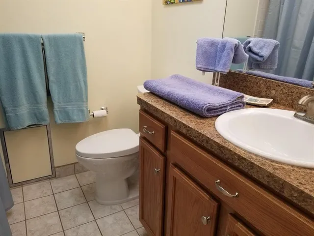 a bathroom with a granite countertop sink toilet and mirror