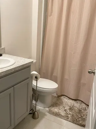 a bathroom with a granite countertop sink and a toilet