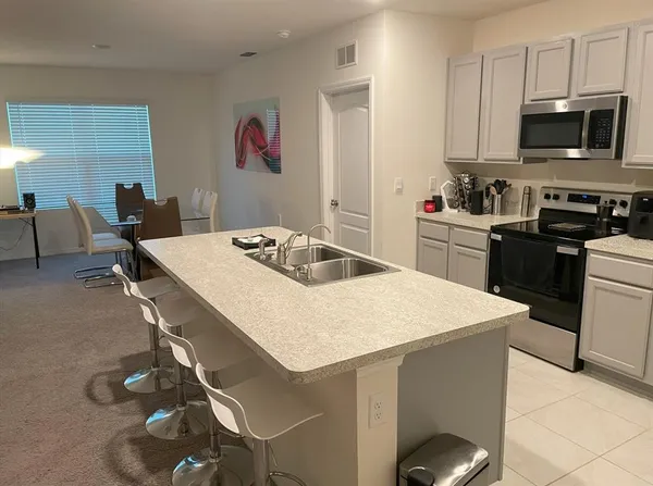 a kitchen with a sink a stove and chairs