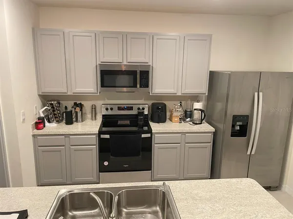 a kitchen with stainless steel appliances granite countertop a refrigerator sink and white cabinets