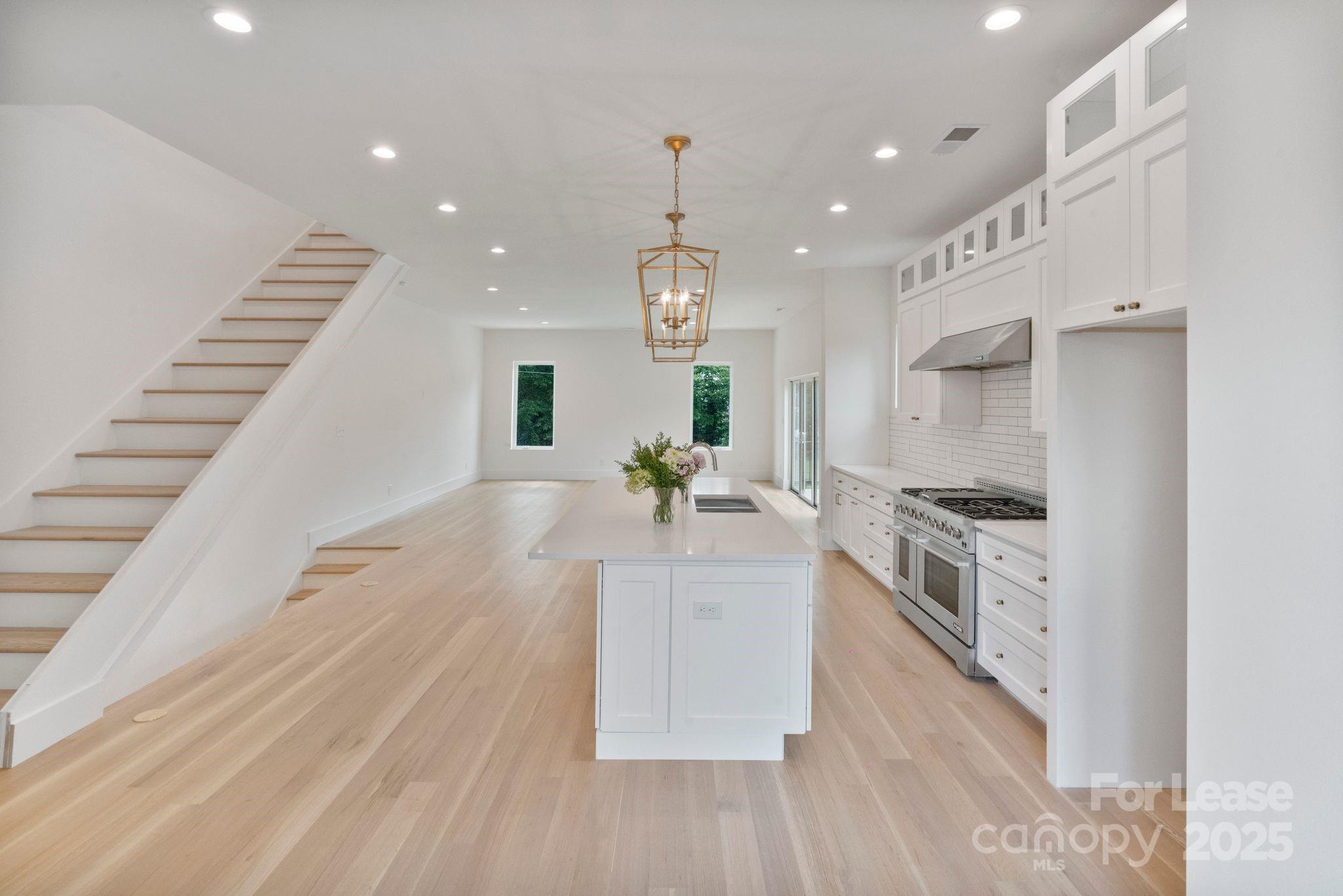 129 French Street, Unit B Charlotte, NC 28216 - Photo 6 of 32 a large white kitchen with stainless steel appliances granite countertop a sink dishwasher a stove and a dining table with wooden floor
