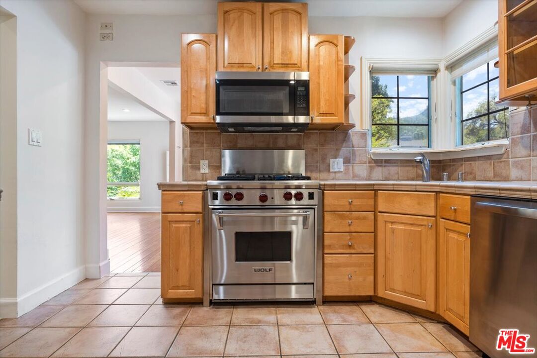 14041 Roblar Road Sherman Oaks, CA 91423 - Photo 15 of 47 a kitchen with stainless steel appliances a stove microwave and cabinets