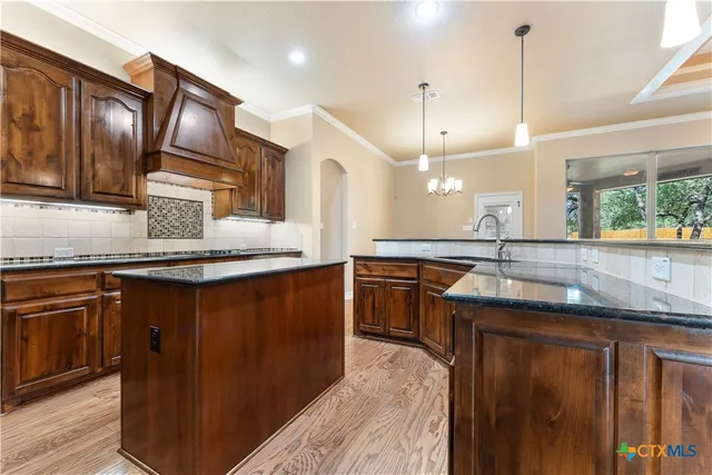 a kitchen with kitchen island granite countertop wooden cabinets and stainless steel appliances