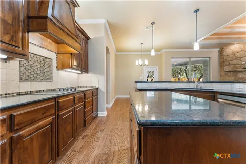 a kitchen with stainless steel appliances granite countertop a sink a stove and a wooden floor