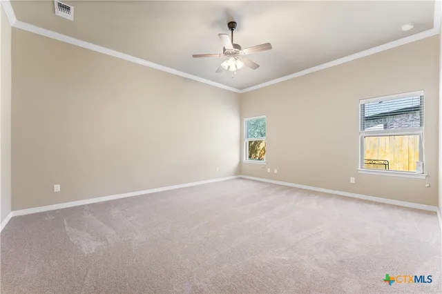 an empty room with a chandelier fan and windows