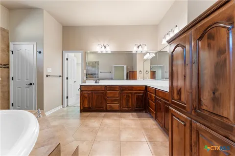 a large bathroom with a tub sink and mirror