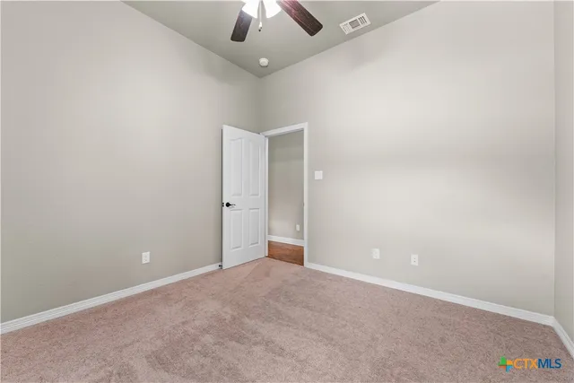 an empty room with a ceiling fan and a window