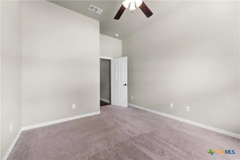 an empty room with ceiling fan and window