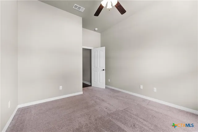 an empty room with ceiling fan and window