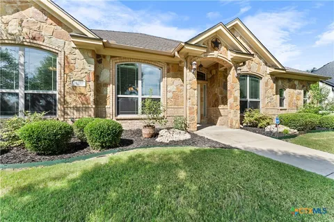 a front view of a house with a yard and potted plants