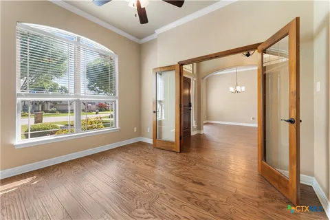 a view of an empty room with a window and wooden floor
