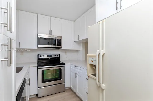 a kitchen with stainless steel appliances a stove a sink a microwave and cabinets