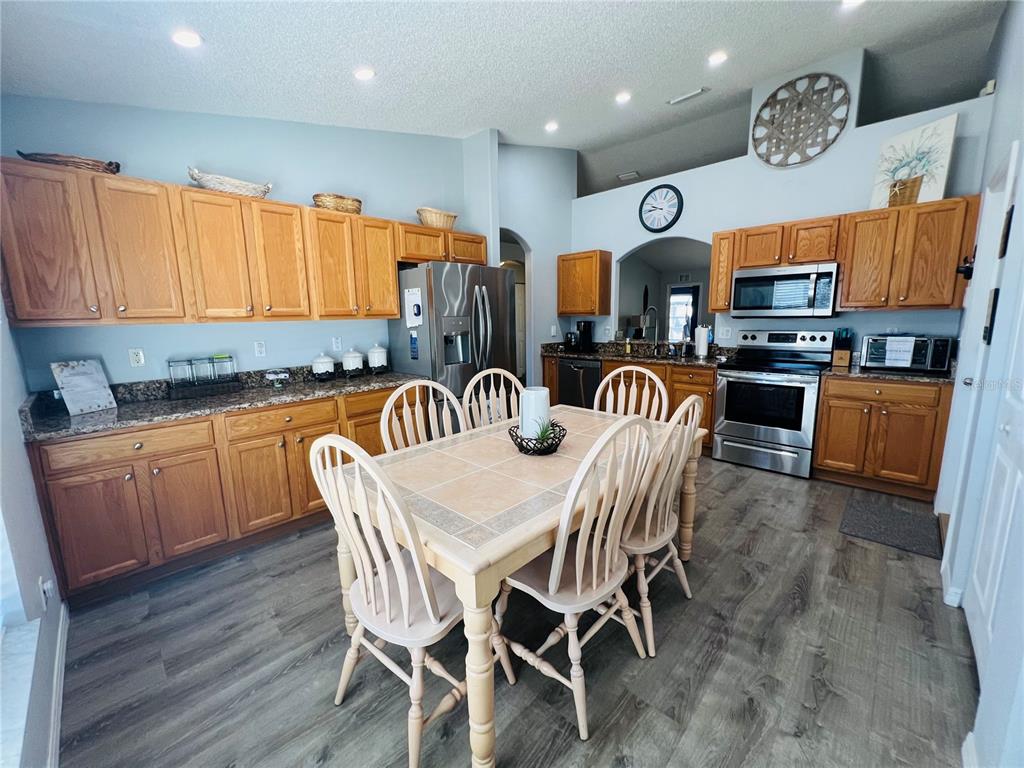 8 Firethorn Lane Palm Coast, FL 32137 - Photo 12 of 28 a kitchen with stainless steel appliances granite countertop a stove top oven a sink a dining table and chairs with wooden floor