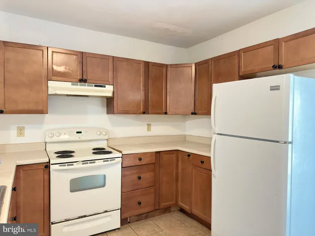a white refrigerator freezer and a stove sitting inside of a kitchen with granite countertop cabinets