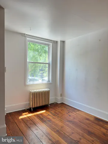 an empty room with wooden floor and window