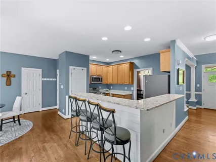 a kitchen with granite countertop a stove a sink a dining table and chairs