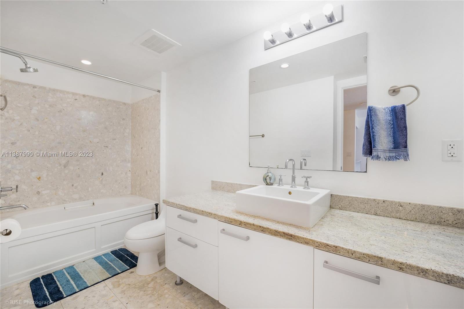 185 Southwest 7th Street, Unit 2204 Miami, FL 33130 - Photo 11 of 29 a bathroom with a granite countertop sink a toilet a mirror a bathtub and shower