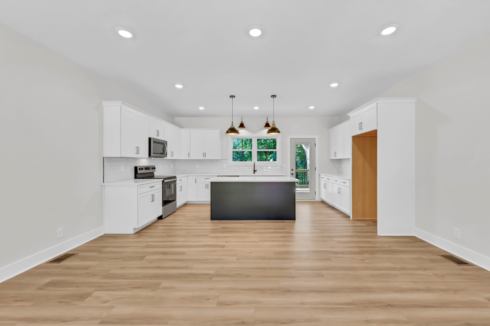 5570 Chambers Road Cumberland Furnace, TN 37051 - Photo 11 of 55 a large white kitchen with kitchen island a sink wooden floor and a refrigerator