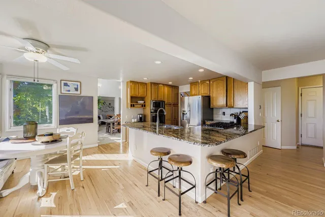 a dining hall with stainless steel appliances kitchen island granite countertop a dining table and chairs with wooden floor