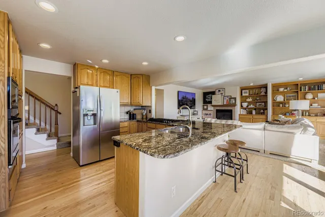 a kitchen with stainless steel appliances granite countertop a refrigerator a stove and a sink with wooden floor