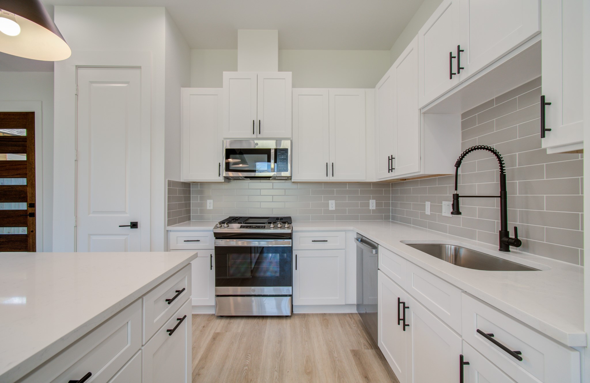 4425 Providence Street Houston, TX 77020 - Photo 11 of 40 a kitchen with stainless steel appliances white cabinets a sink dishwasher a stove and a refrigerator with wooden floor