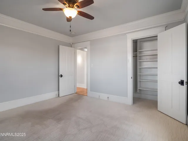 a view of an empty room and chandelier fan