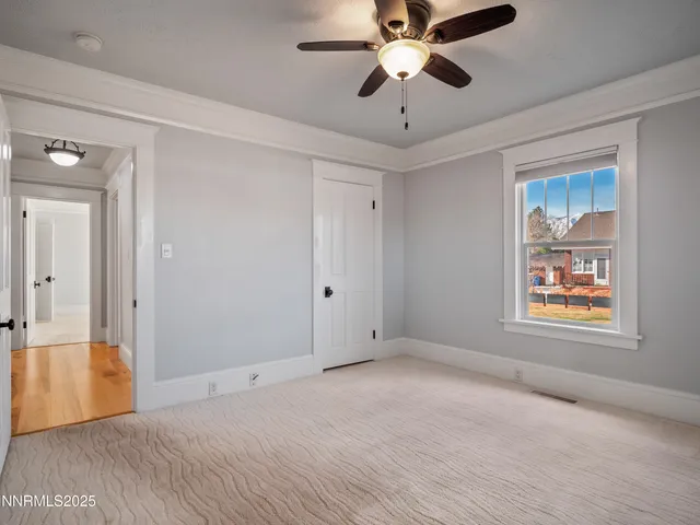 an empty room with windows and fan