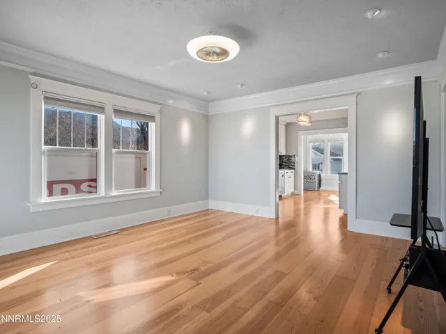 a view of an empty room with wooden floor and a window