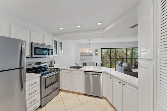 a kitchen with white cabinets stainless steel appliances and a window