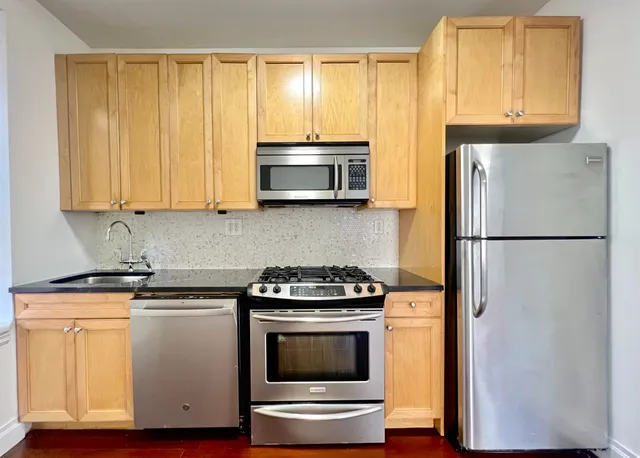a kitchen with stainless steel appliances granite countertop a refrigerator microwave and sink