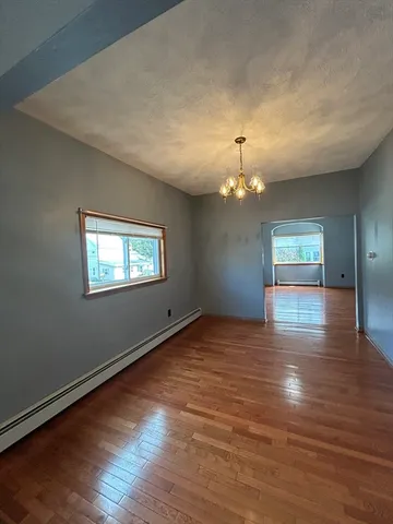 an empty room with wooden floor chandelier and entryway