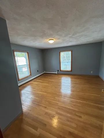 a view of empty room with window and wooden floor
