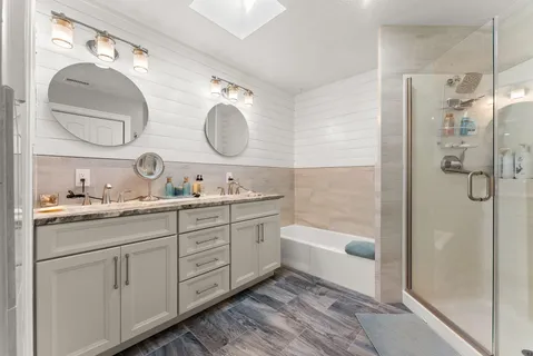 a bathroom with a double vanity sink mirror and bathtub