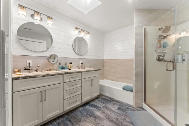 a bathroom with a double vanity sink mirror and bathtub