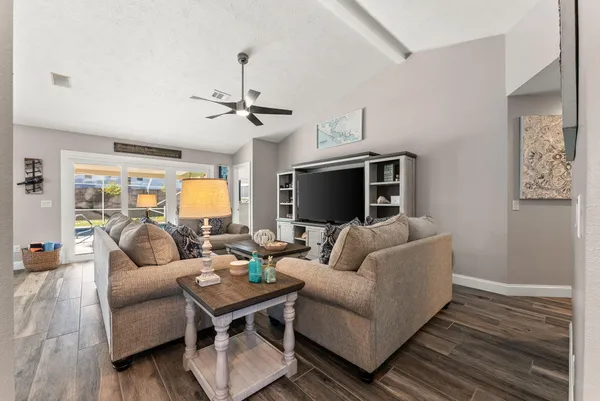 a living room with furniture a ceiling fan and a flat screen tv
