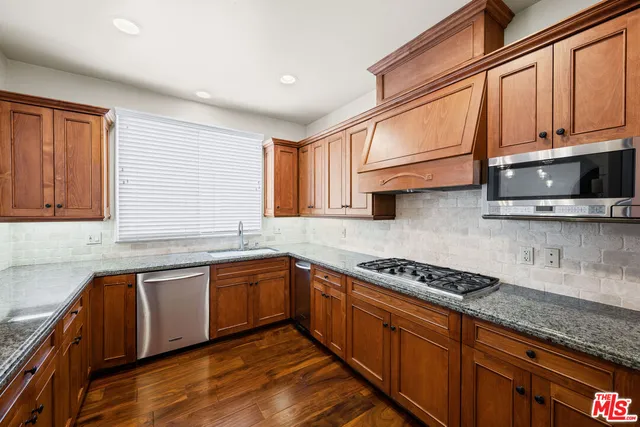 a kitchen with stainless steel appliances granite countertop a sink a stove cabinets and wooden floor
