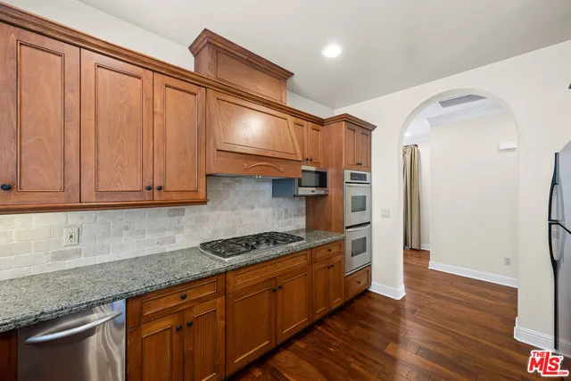 a kitchen with stainless steel appliances granite countertop a stove a sink and a refrigerator